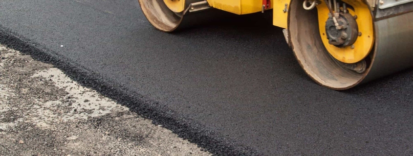 Roller flattening new asphalt pavement