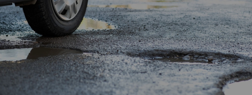 Side view of potholes on wet pavement