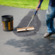Homeowner Spreads Blacktop Asphalt Sealant On Driveway