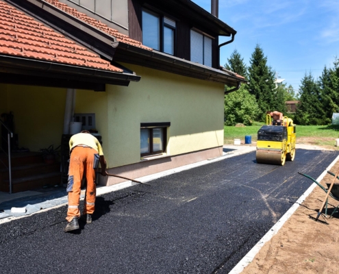 Worker Applying Asaphalt To Residential Drivewy