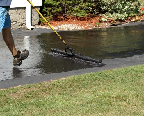 Worker Resurfacing Ashphalt Driveway
