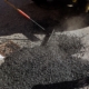 Worker Spreading Asphalt On Road