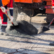 Young Builder On Asphalting Paver Machine During Road Street Repairing Works